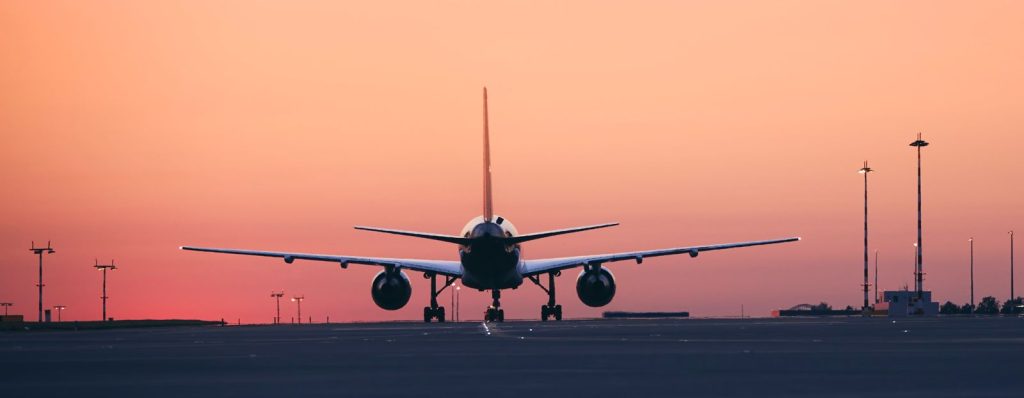 Vliegtuig op de startbaan bij zonsondergang terwijl reizigers online vergelijk goedkope vluchten.
