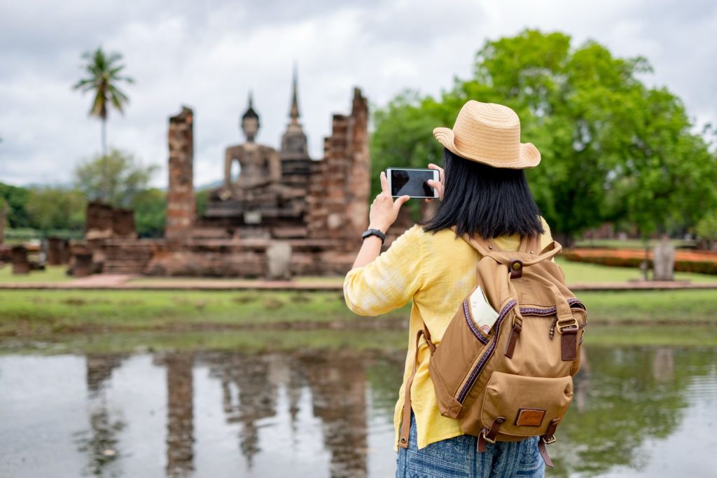 Goedkope vluchten naar mooie bestemmingen met een reiziger die een tempel fotografeert op vakantie.
