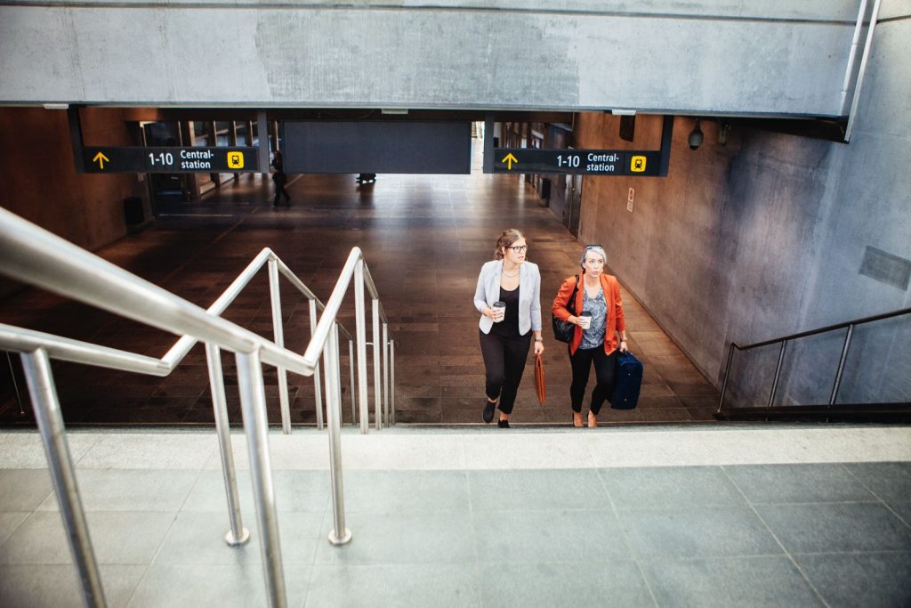 Twee zakenvrouwen lopen met koffie door het station op weg naar de trein na aankomst met hun vliegtickets Istanbul